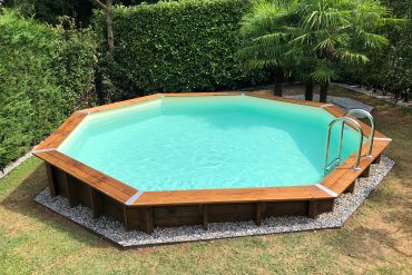 Piscina da giardino in legno Ocean 580, perfettamente integrata nel giardino, circondata da prato verde e spazi relax, per piacevoli momenti all'aperto.