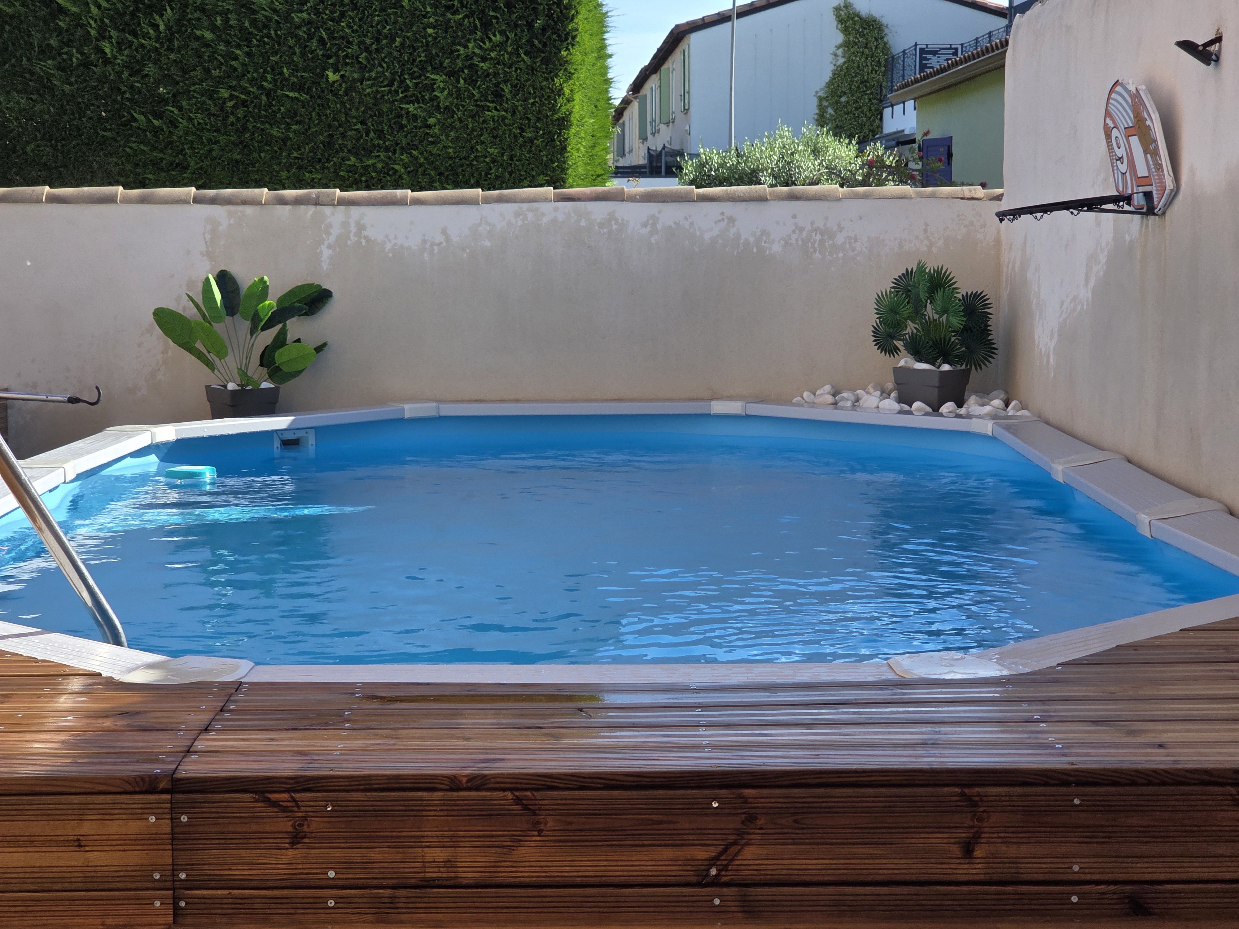 Détail piscine hors sol White Pool en acier avec eau limpide et décorations vertes au bord du bassin