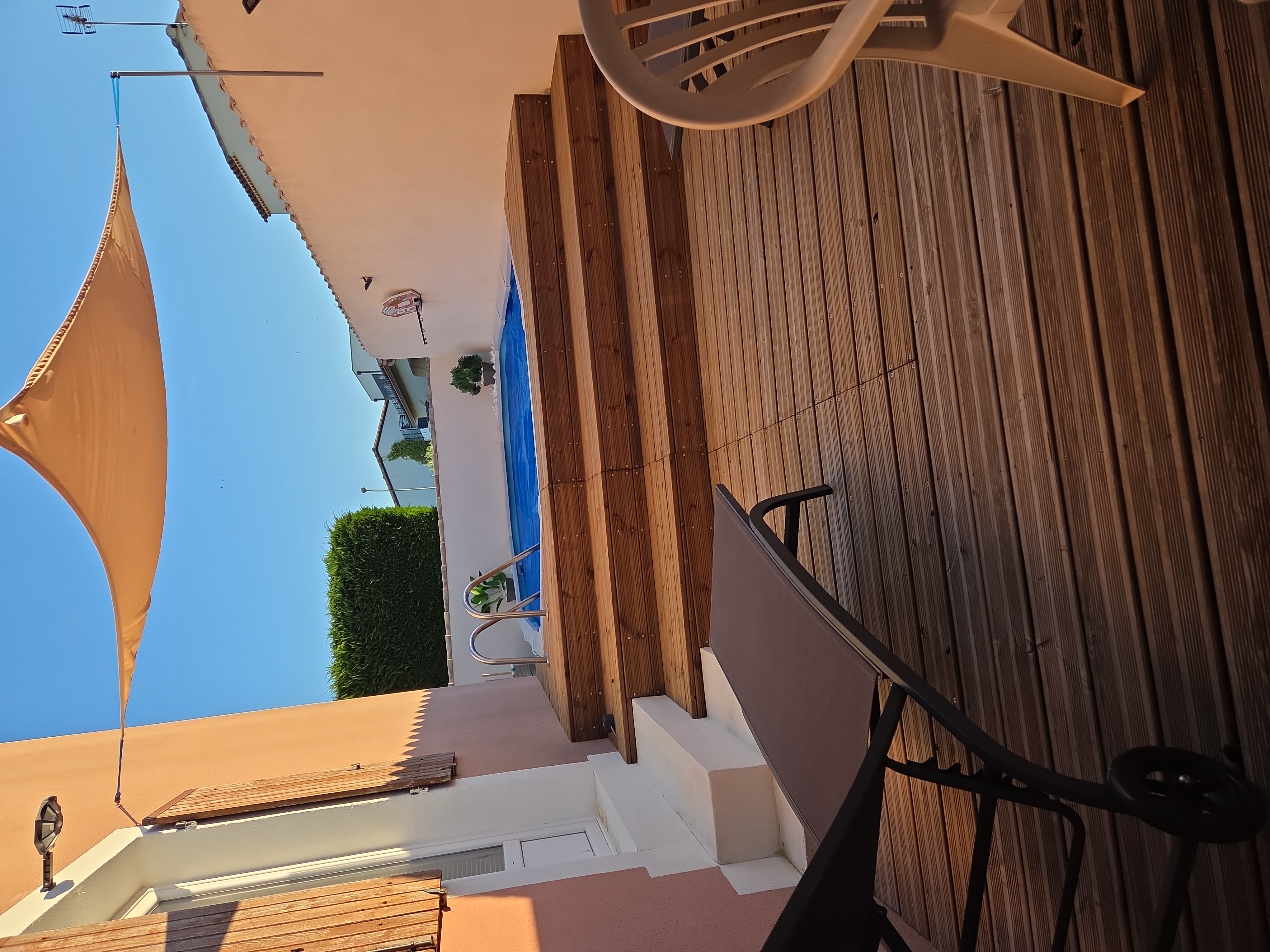 Piscine ovale en acier hors sol avec espace détente, voile d’ombrage et transats dans jardin privé