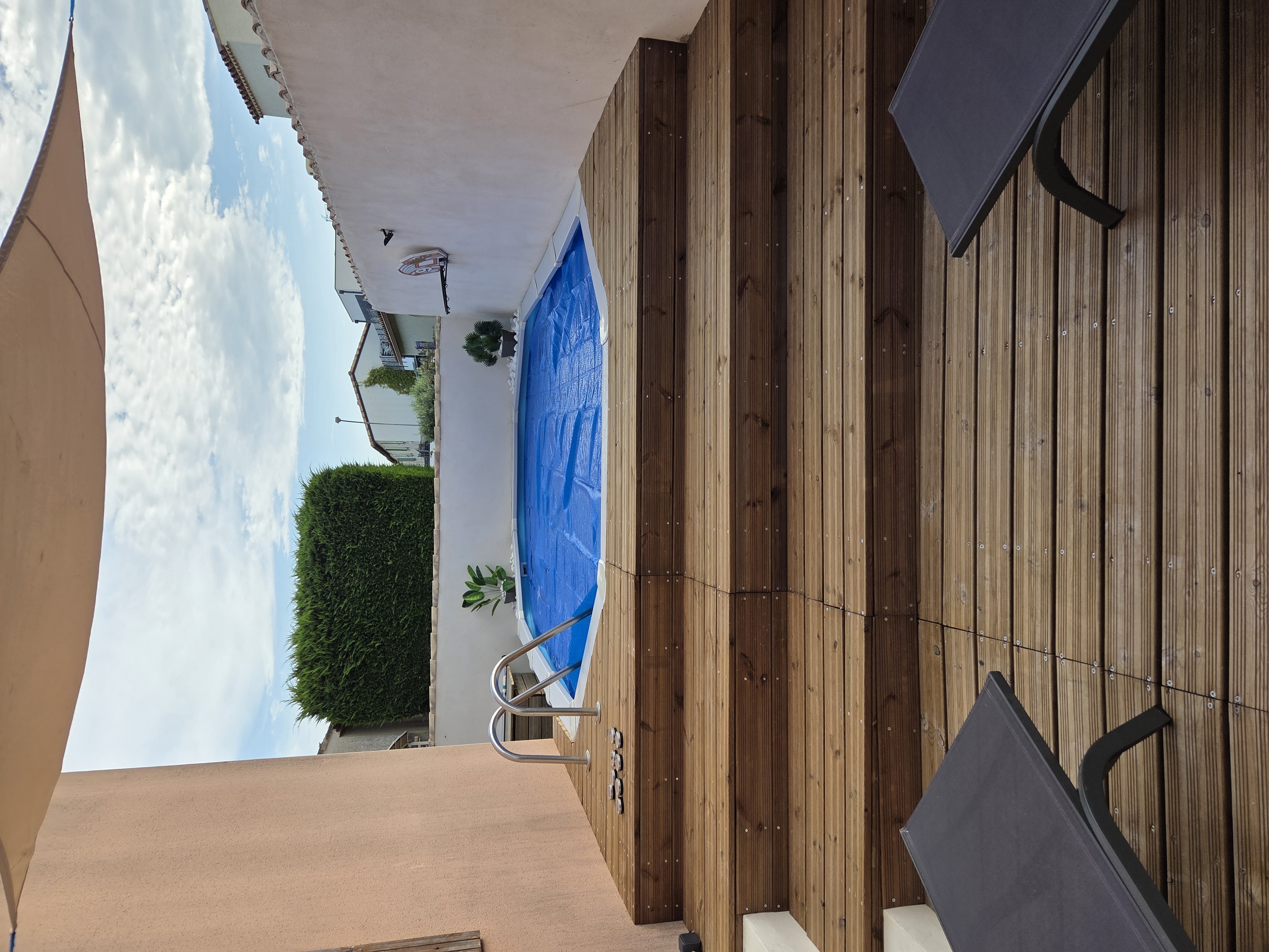 Vue frontale piscine hors sol White Pool 610x360 cm avec couverture thermique bleue et solarium en bois